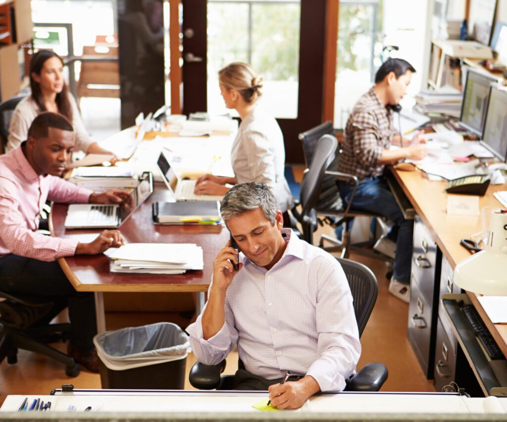 people in an office with loads of paperwork around them
