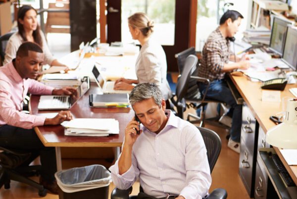 people in an office with loads of paperwork around them