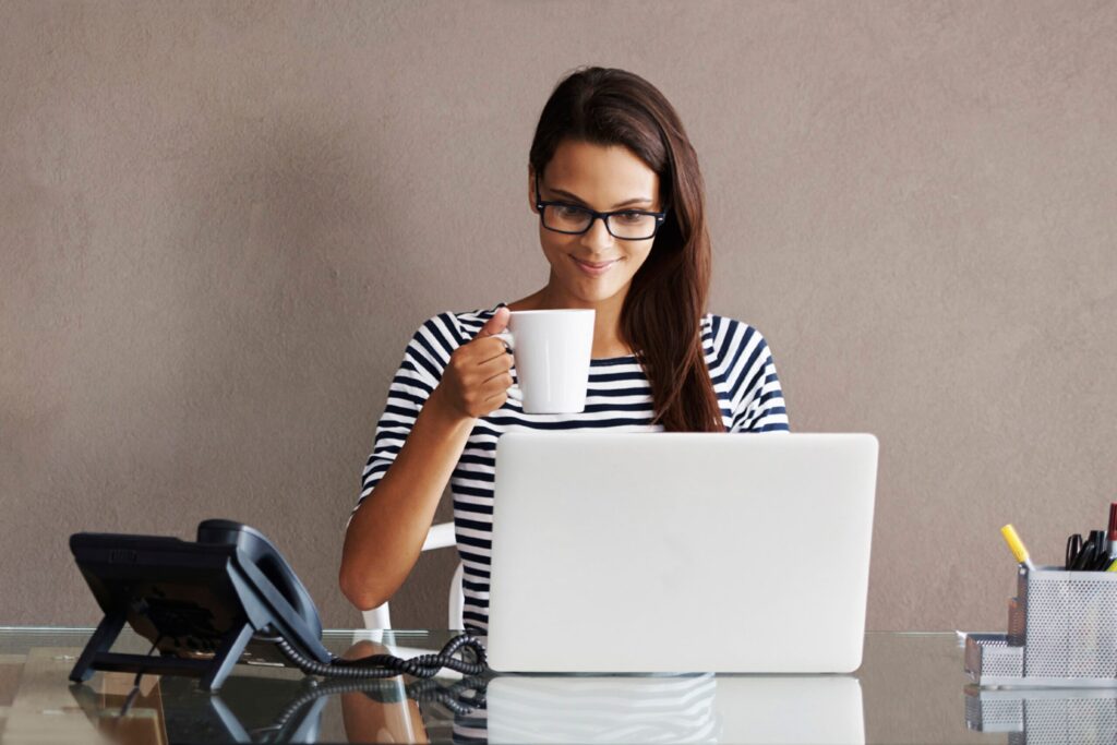 An attractive young businesswoman having coffee while sitting at her office desk
